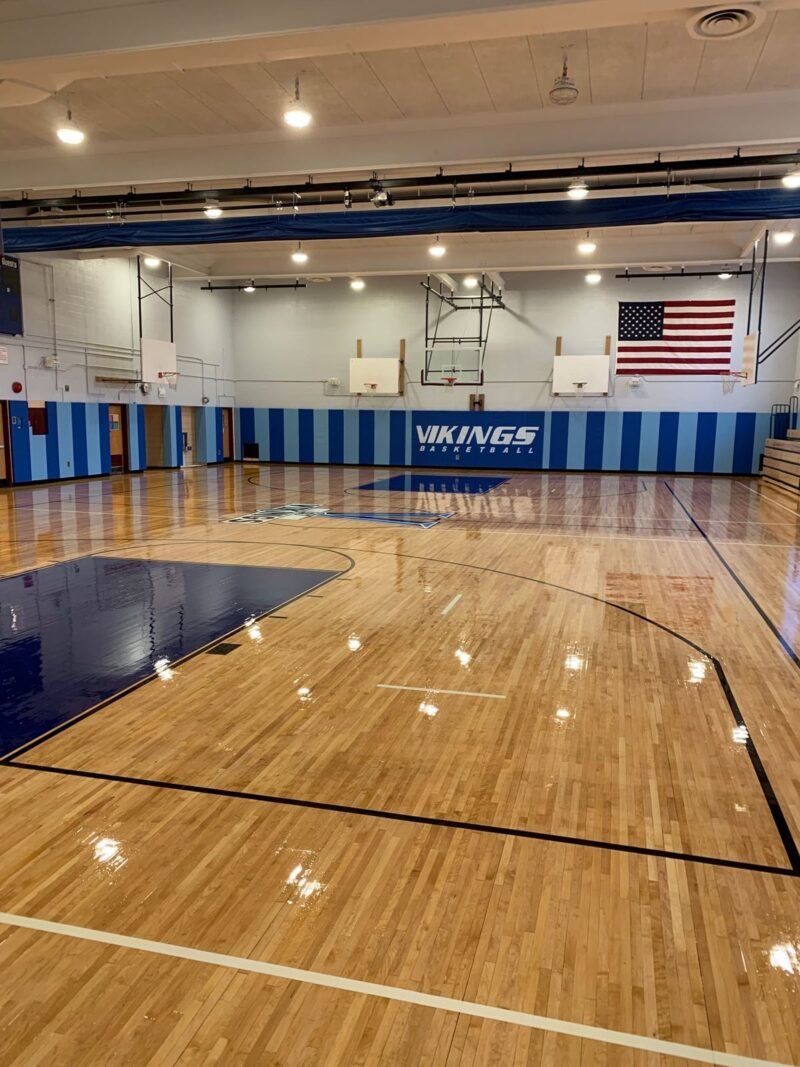 Gymnasium with refinished hardwood floor, wall padding and flag