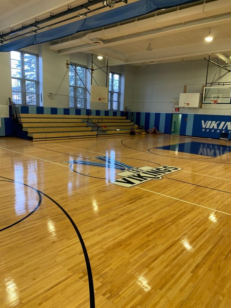 Gymnasium floor with center court logo and wood bleachers