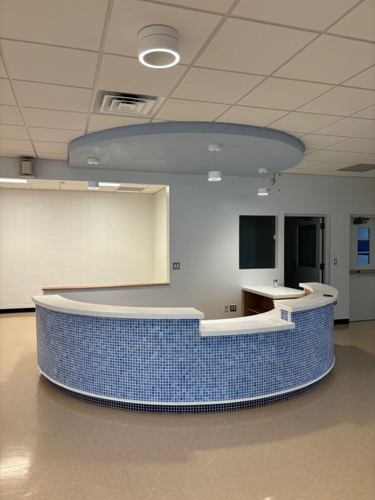 Curved reception desk in blue mosaic tile under a round ceiling soffit